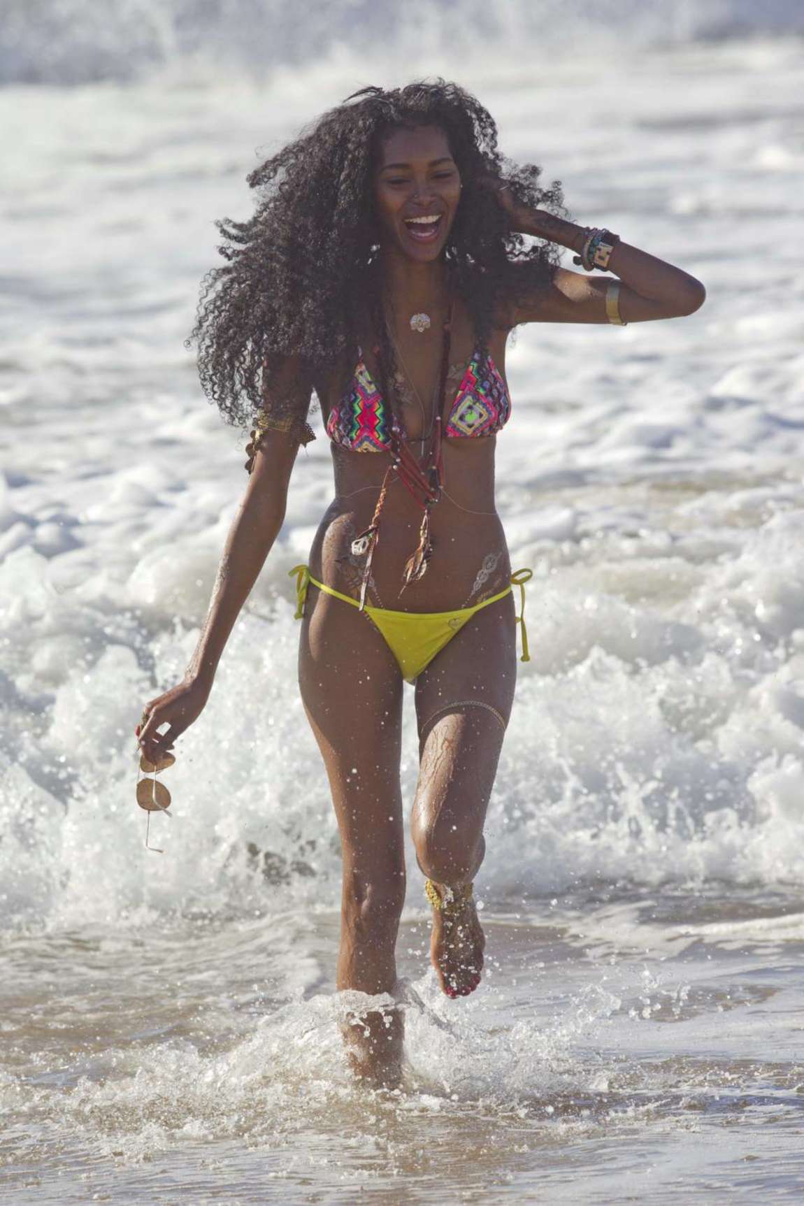 Med hendes slank krop og Sort hårtype, uden BH (størrelse 32C) på stranden i bikini
