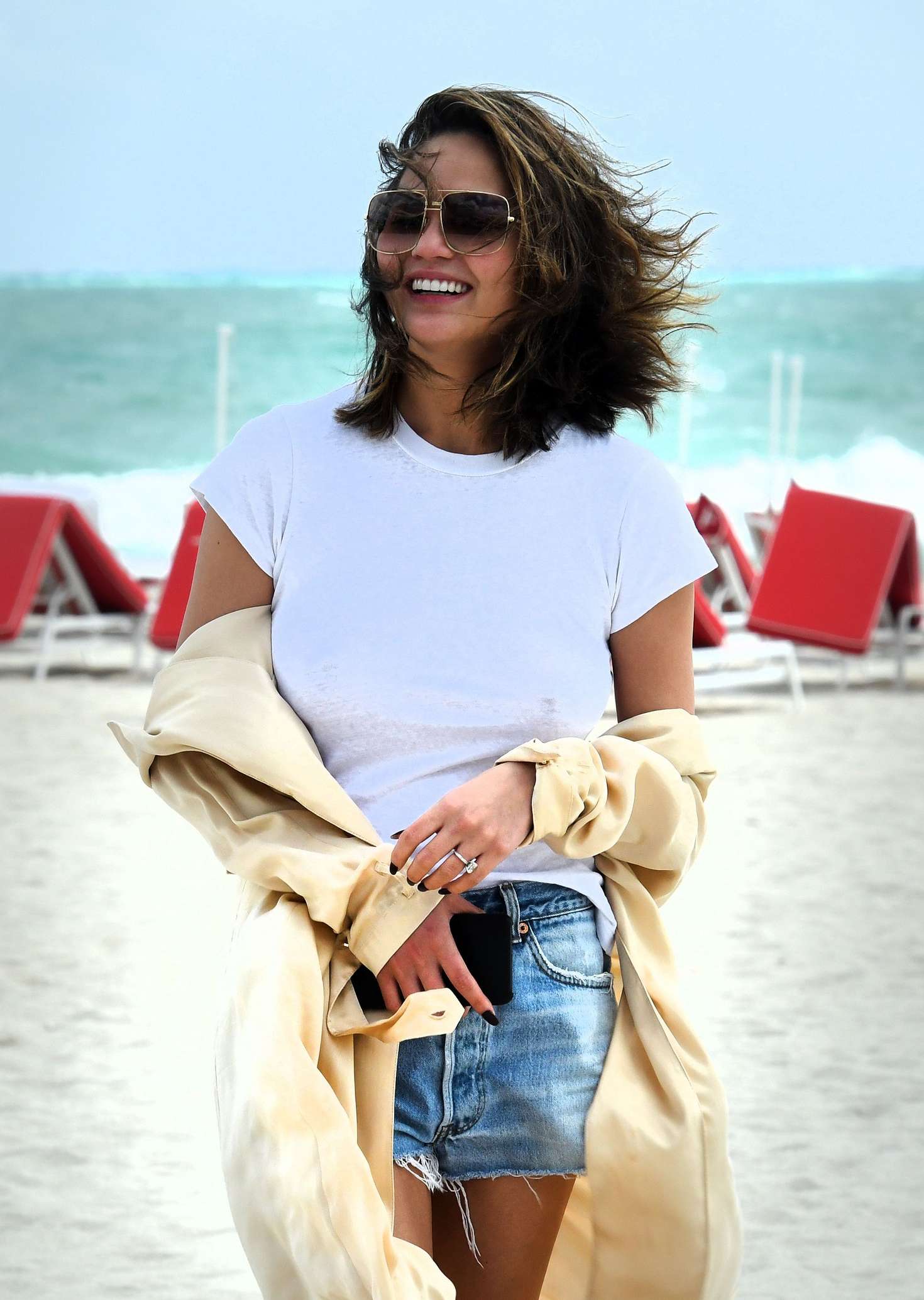 Chrissy Teigen in Jeans Shorts on the Beach in Miami. 