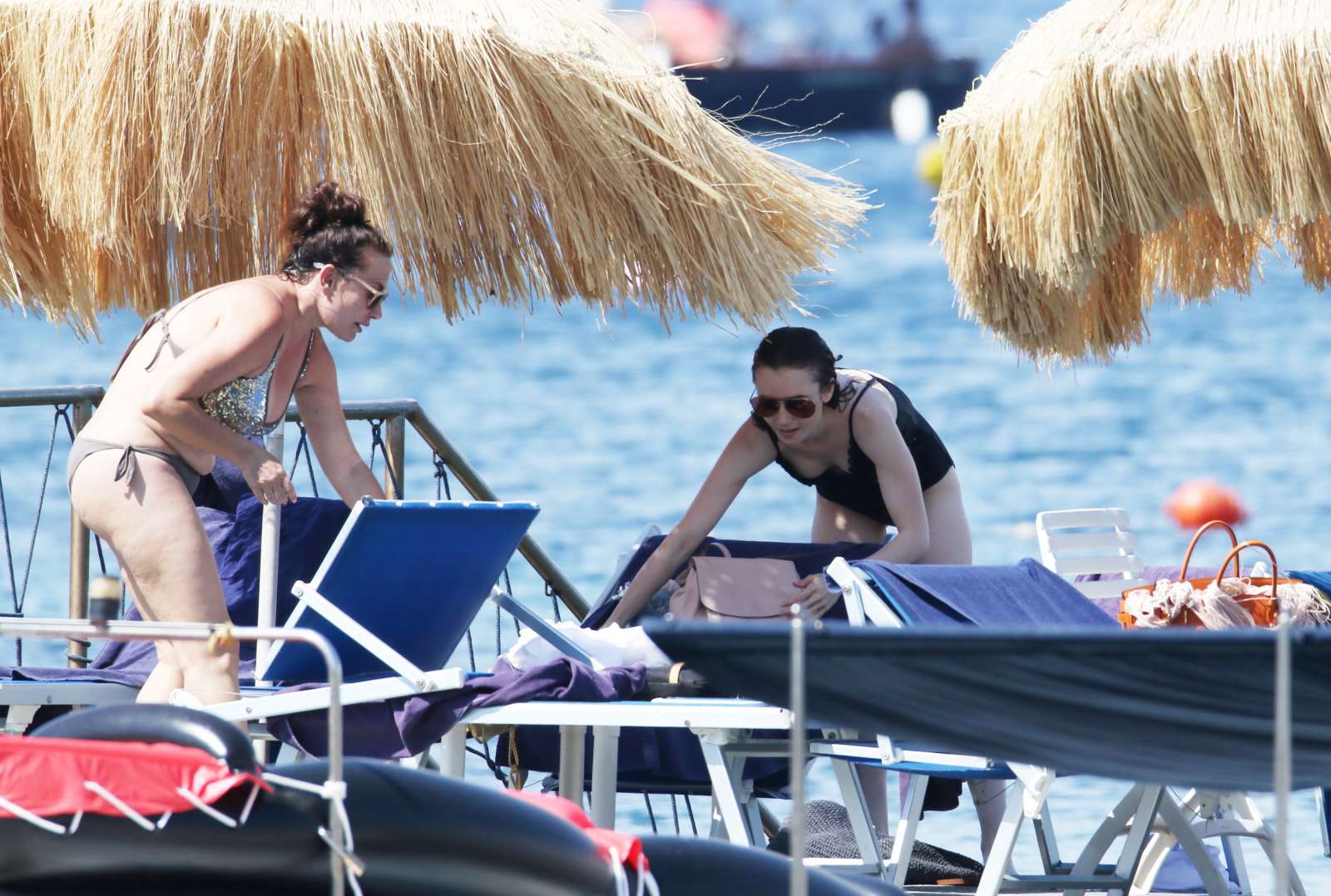 Lily Collins in Black Swimsuit at a beach in Ischia. 