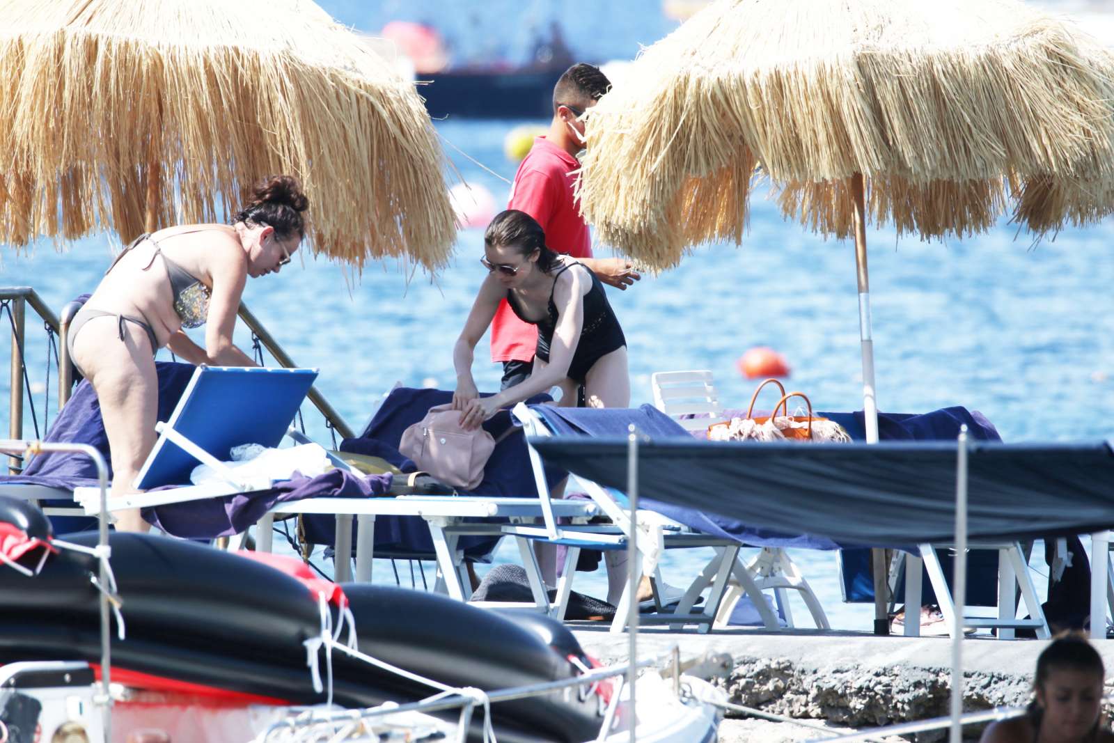 Lily Collins in Black Swimsuit at a beach in Ischia. 