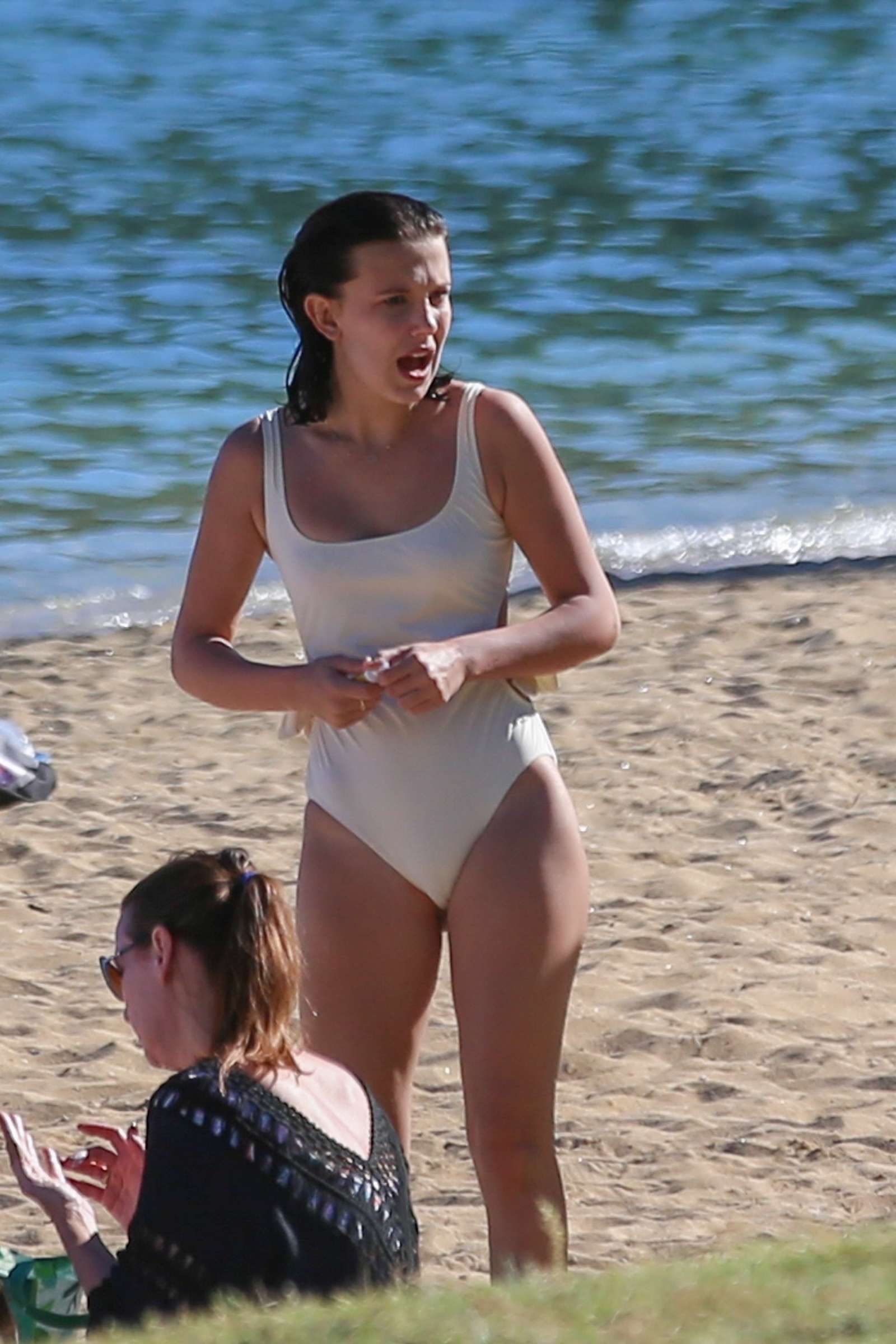 Millie Bobby Brown in White Swimsuit on the beach in Honolulu. 