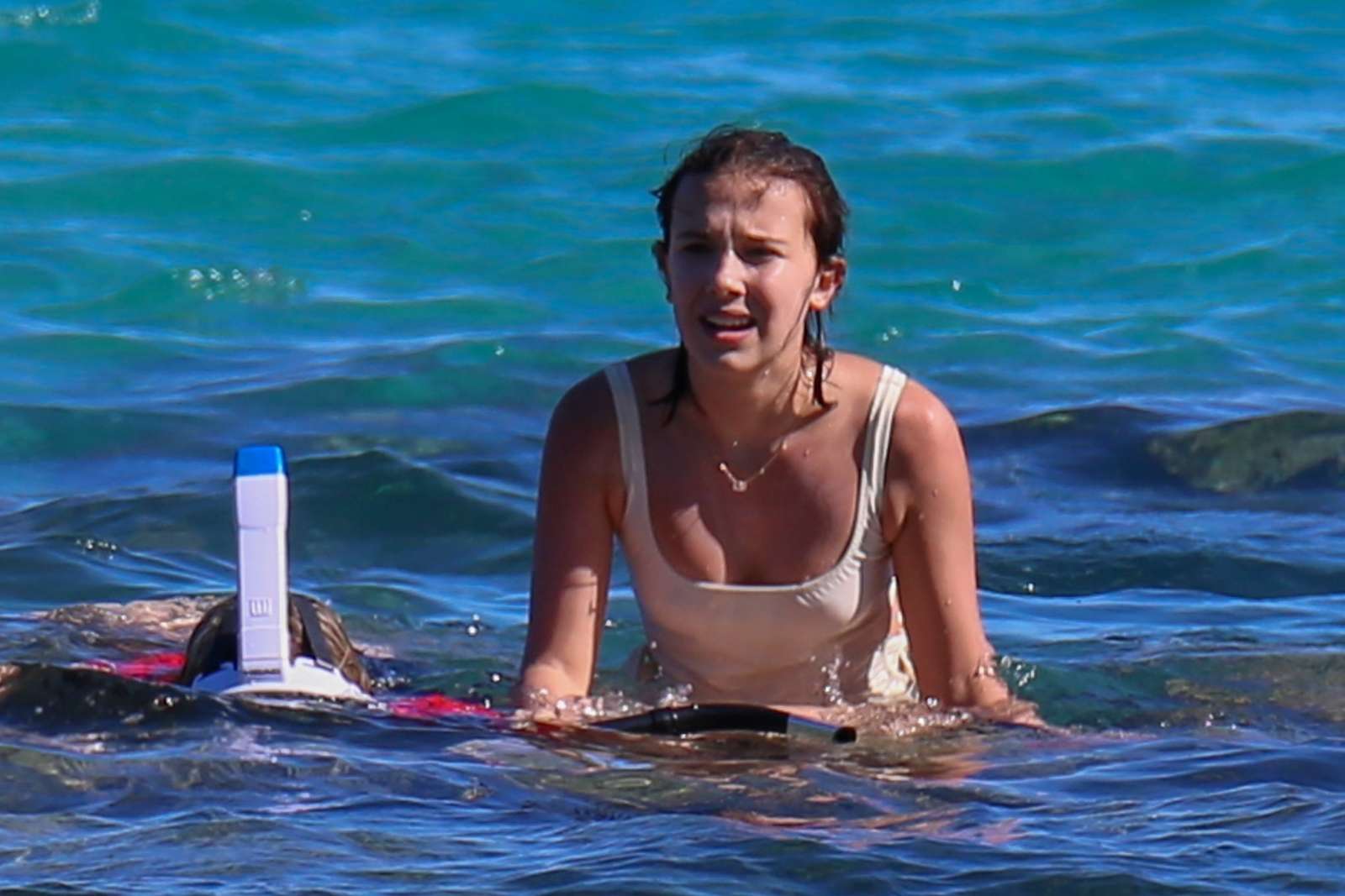 Millie Bobby Brown in White Swimsuit on the beach in Honolulu. 